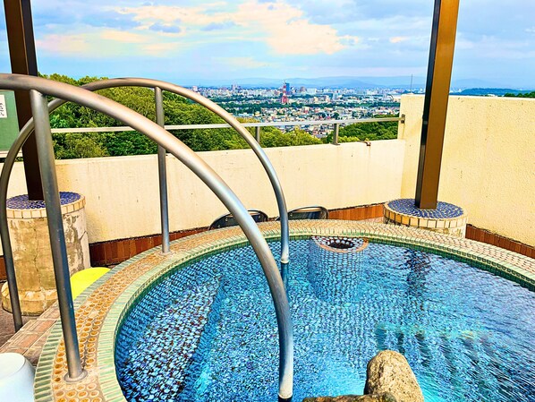 Una piscina en la azotea con vistas a la ciudad, barandillas de metal y baldosas de mosaico.