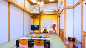 A traditional Japanese-style room with tatami flooring, a low table with cushions, a television, and a decorative vase. - Takasago onsen (Asahikawa)