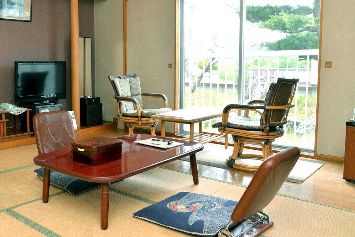 A traditional Japanese-style living room with tatami flooring, a low table, and two tatami mats.