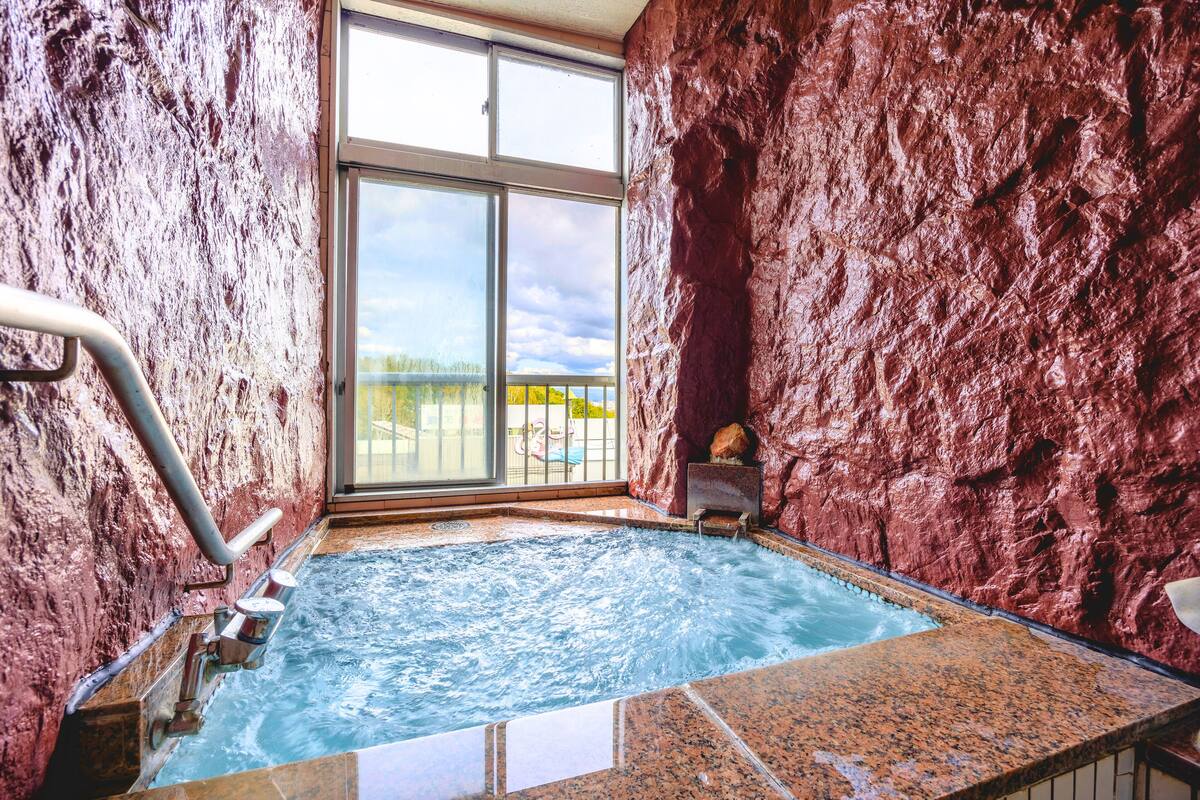 A hot tub with a rocky wall and a large window.