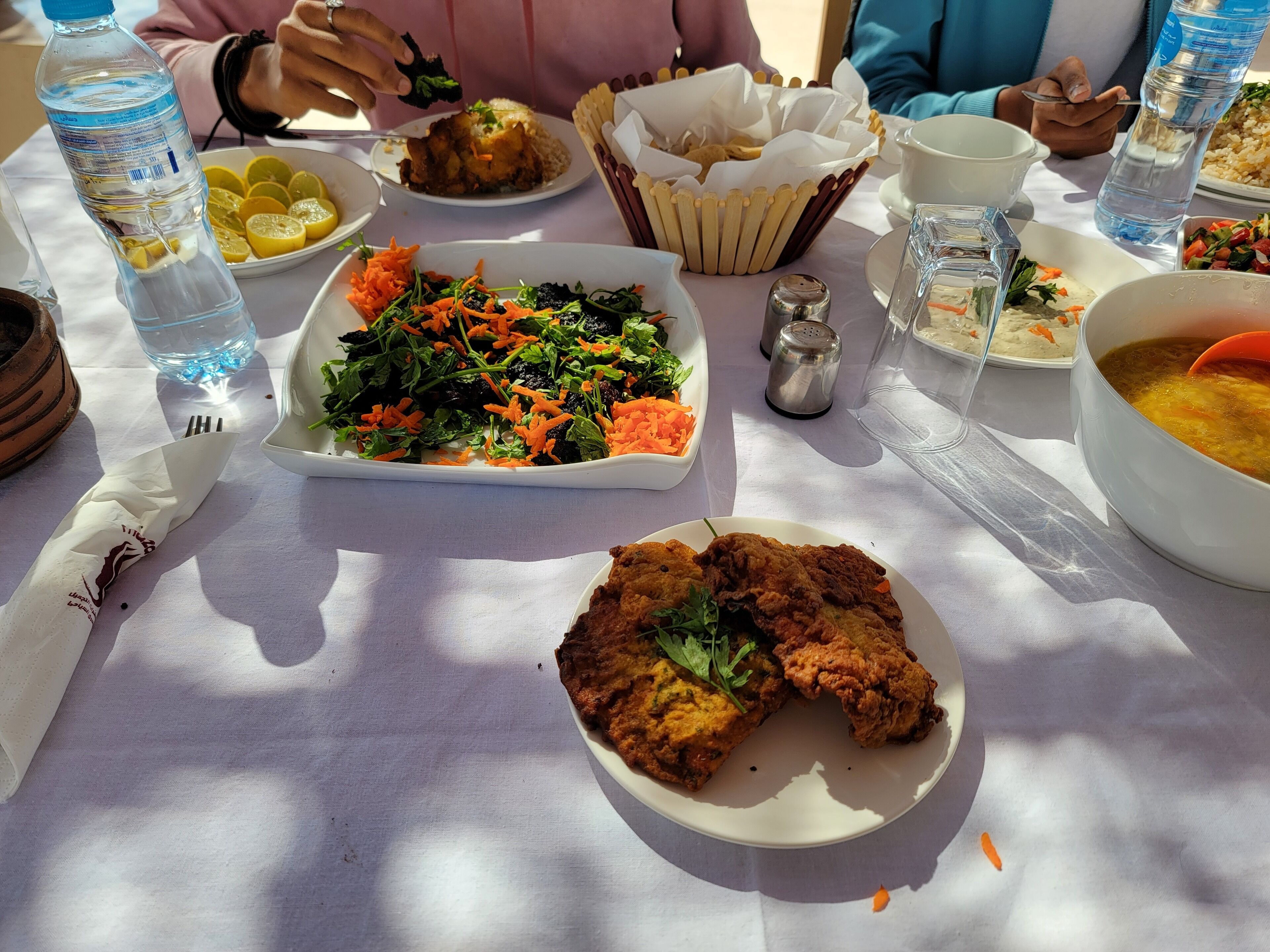 A table with various dishes including a salad, fried chicken, and a bowl of soup.