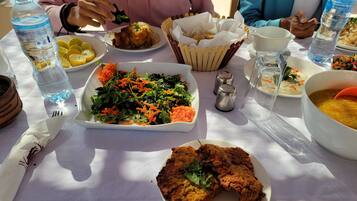 A table with various dishes including a salad, fried chicken, and a bowl of soup.