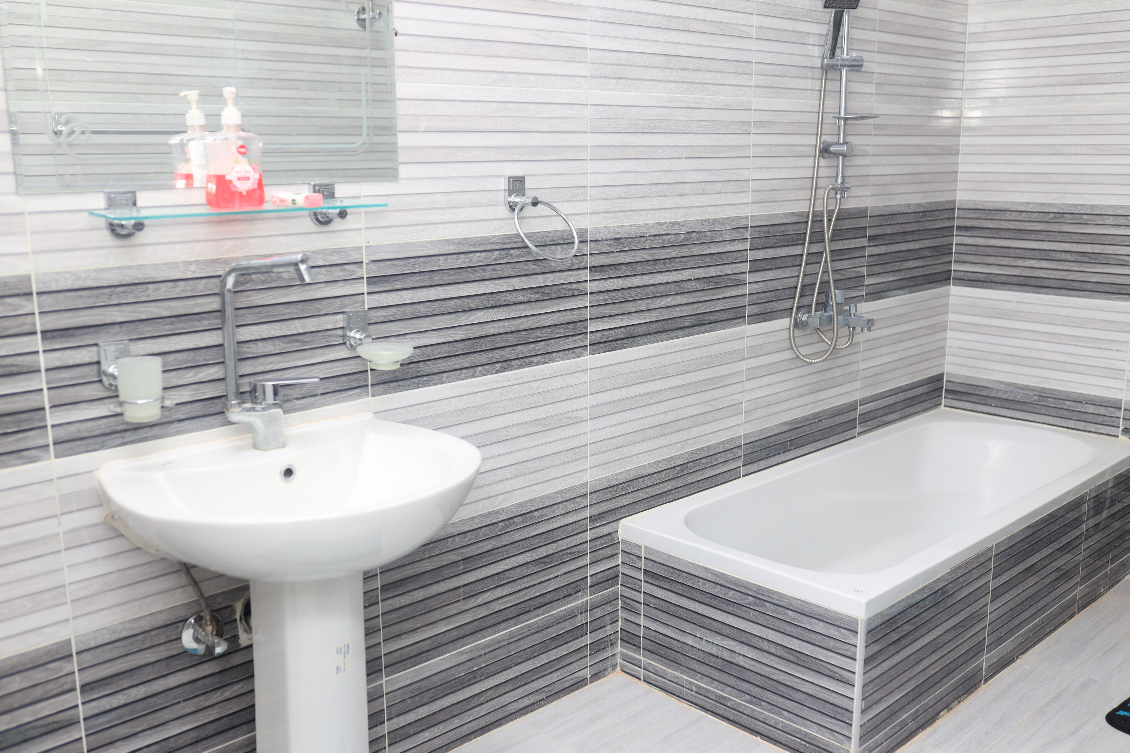 A modern bathroom with a white sink, a bathtub, and a shower.
