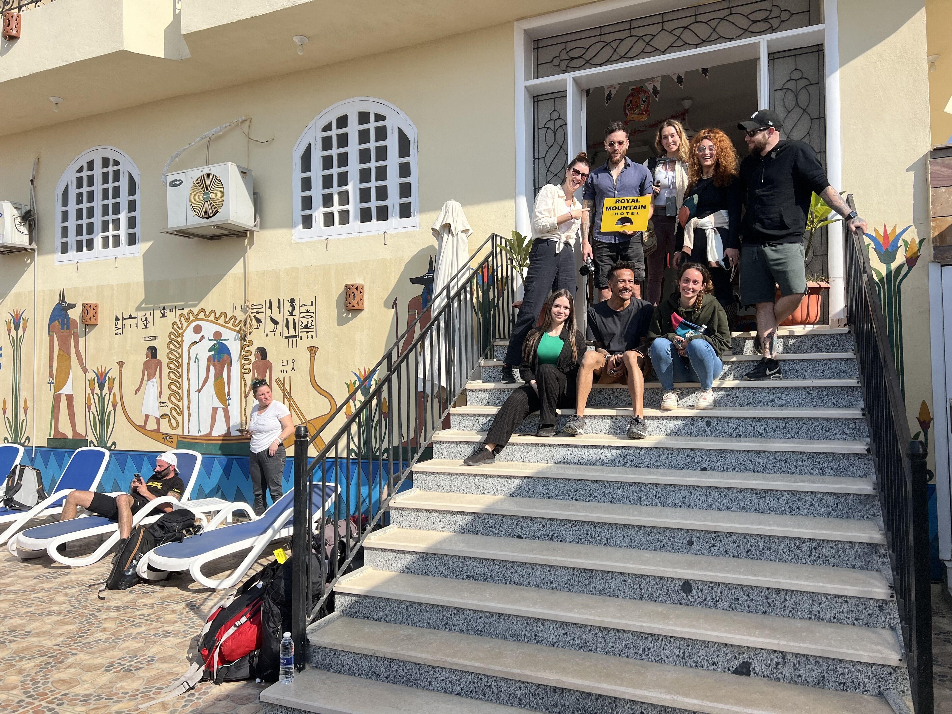 A group of people ascending a set of stairs with a mural of Egyptian figures on the wall.