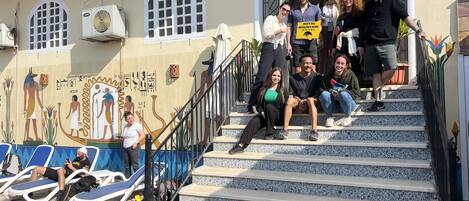 A group of people ascending a set of stairs with a mural of Egyptian figures on the wall.