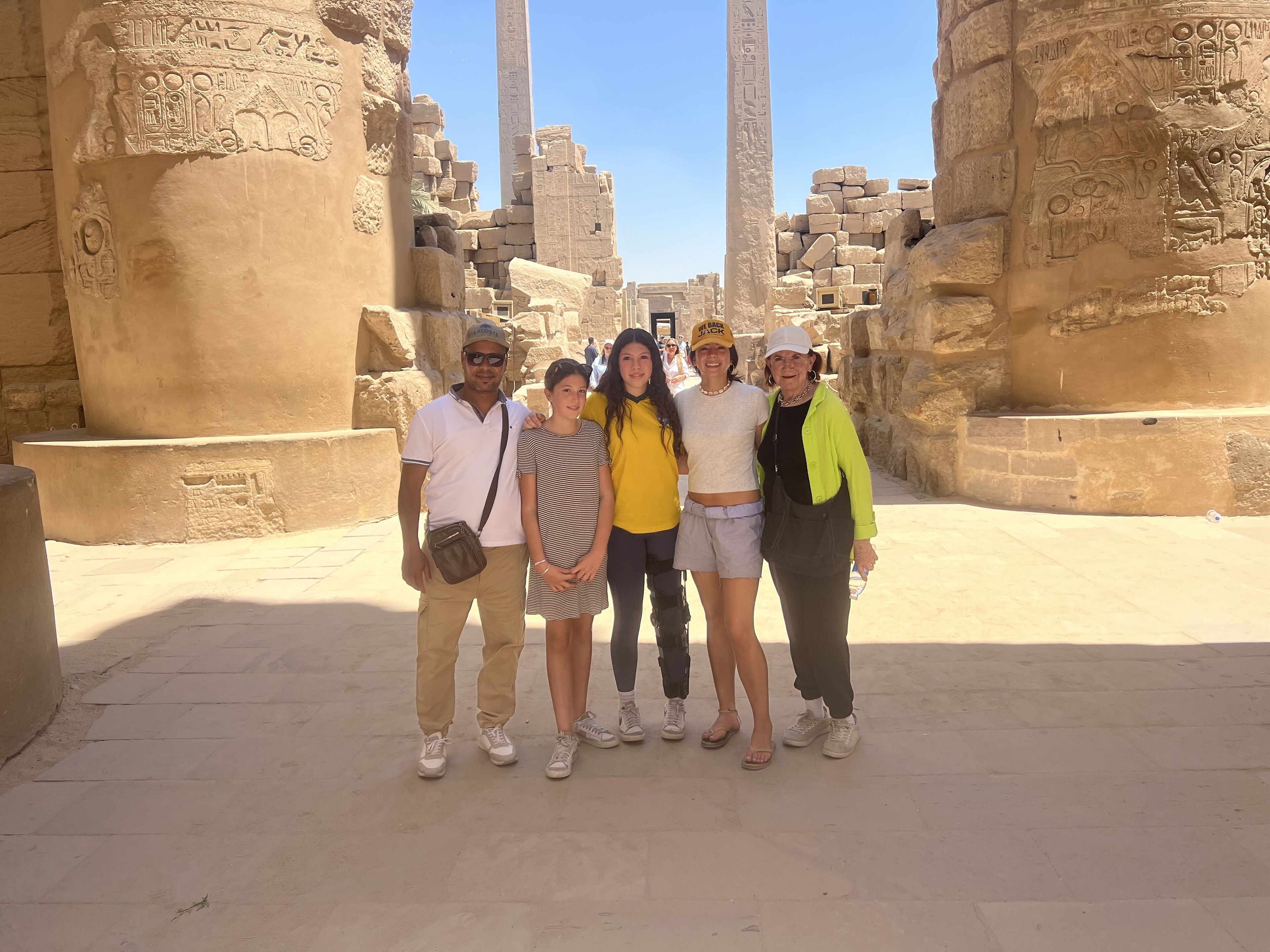 Un grupo de personas frente a unas ruinas egipcias antiguas con jeroglíficos y columnas.