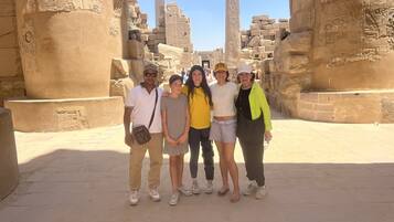 Un grupo de personas frente a unas ruinas egipcias antiguas con jeroglíficos y columnas.