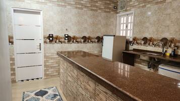 Una cocina con encimera de granito, pileta integrada y refrigerador.