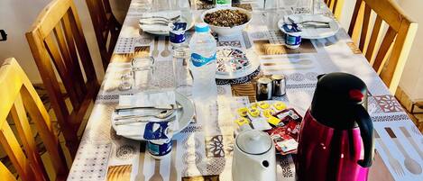 Una mesa de comedor con platos, cubiertos, vasos y una termo.