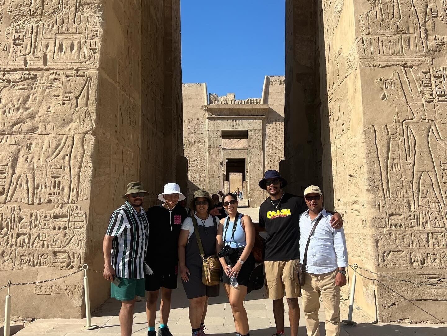 A group of people standing in front of ancient Egyptian hieroglyphs.