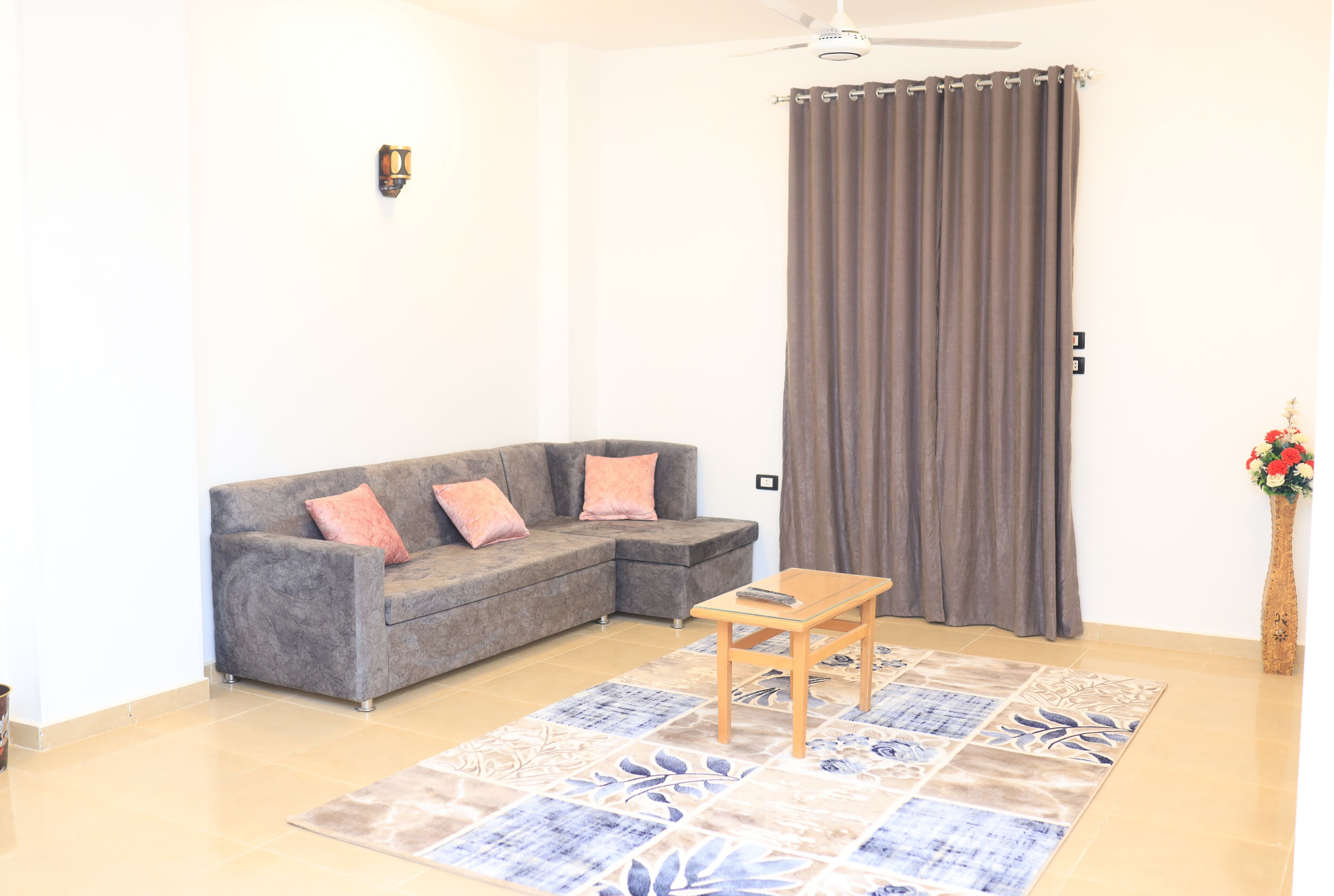 A living room with a grey sectional sofa, a wooden coffee table, and a patterned rug.