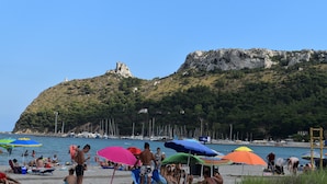 A beach with people sunbathing and swimming, colorful umbrellas, and boats in the background. - DELEDDA HOME (Cagliari)