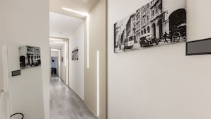 A hallway with a fire extinguisher, a door with a sign, and a wall with a black and white photograph. - DELEDDA HOME (Cagliari)