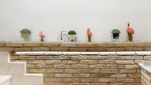 A brick fireplace with decorative items including a flamingo, a bicycle, and potted plants. - DELEDDA HOME (Cagliari)