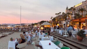 A bustling outdoor dining area with tables and chairs, overlooking a waterfront. - Beautiful 120m2 Flat in bourgeois building with terrace (Cannes)