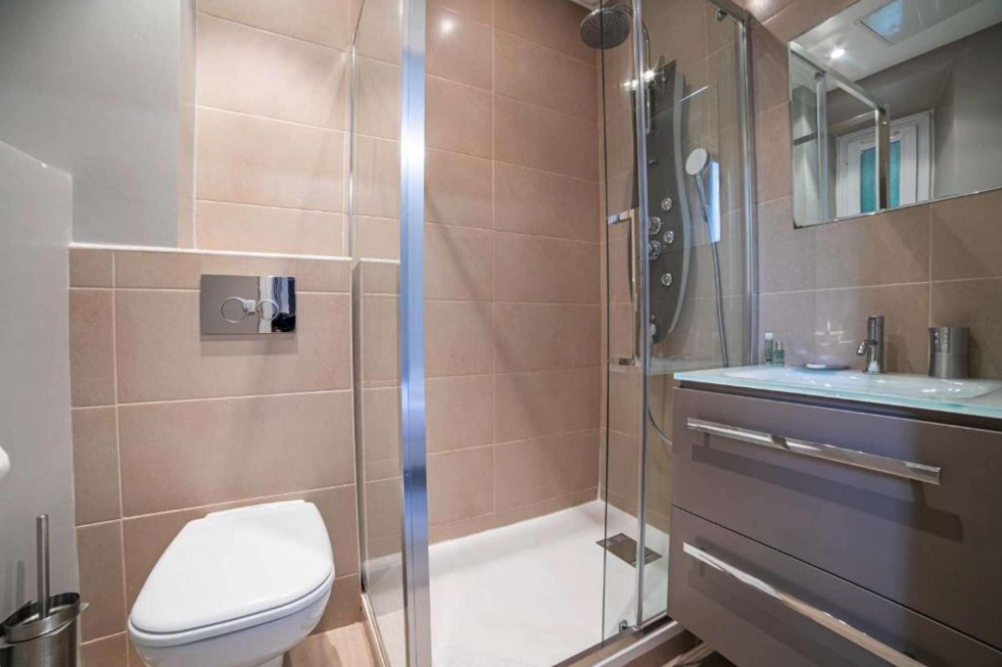 A modern bathroom with a glass shower enclosure, a white toilet, and a vanity with a mirror.