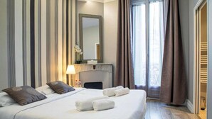 A hotel room with a large bed, a fireplace, a mirror, and a view of the outdoors. - Beautiful 120m2 Flat in bourgeois building with terrace (Cannes)