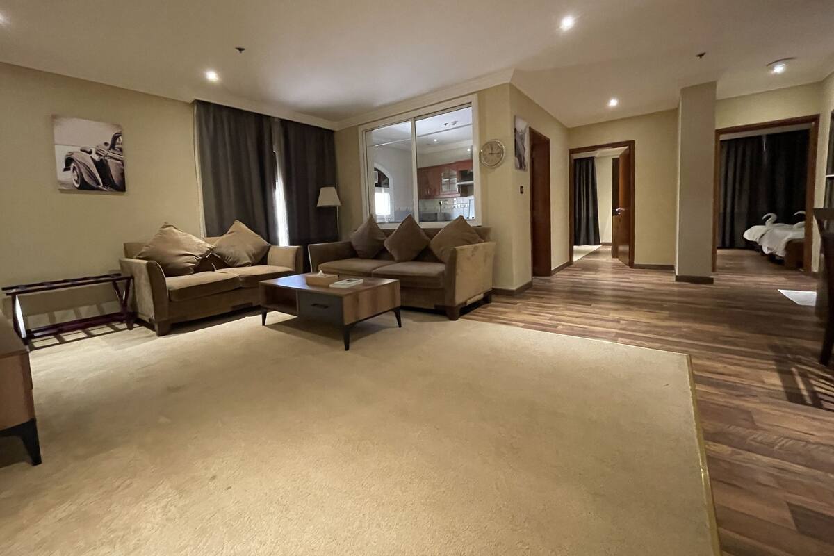 A spacious living room with a sofa set, a coffee table, and a large mirror.
