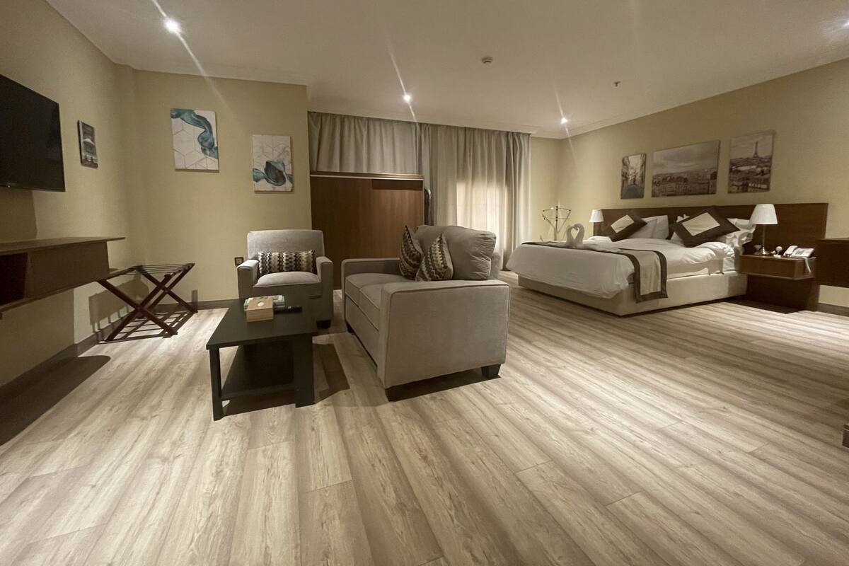 A modern hotel room with a sofa, armchair, and a bed.