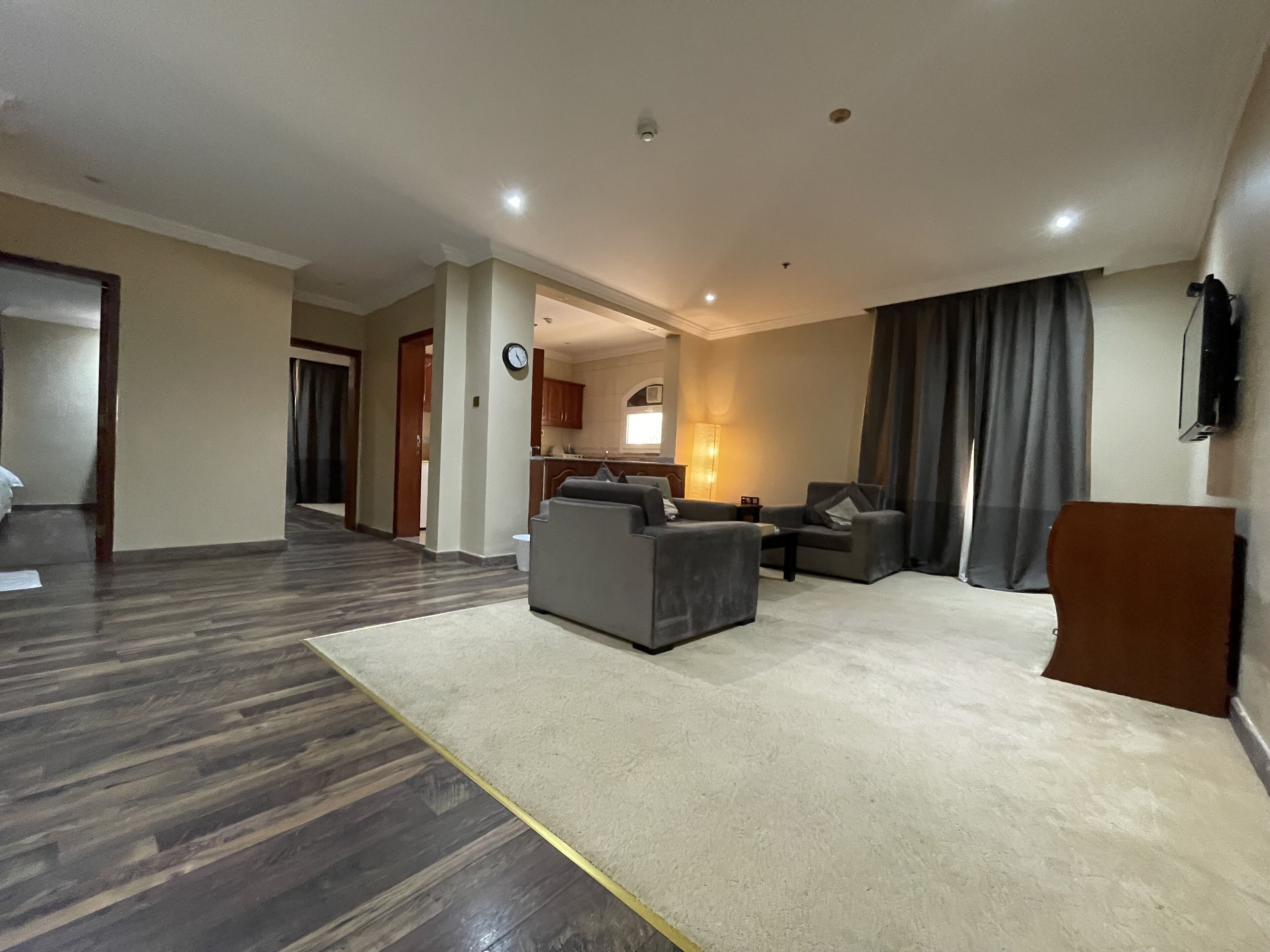Un amplio espacio de sala con un conjunto de sofás, una mesa de centro y un televisor montado en la pared.