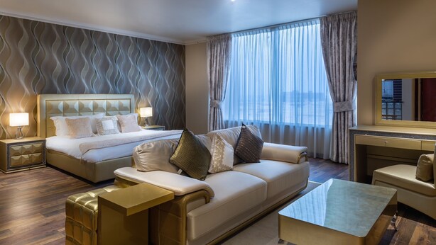 Une chambre d’hôtel avec un grand lit, un canapé, une table basse et un téléviseur.