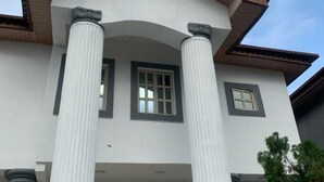 Un bâtiment à la façade blanche, doté de deux colonnes et d’une petite fenêtre.