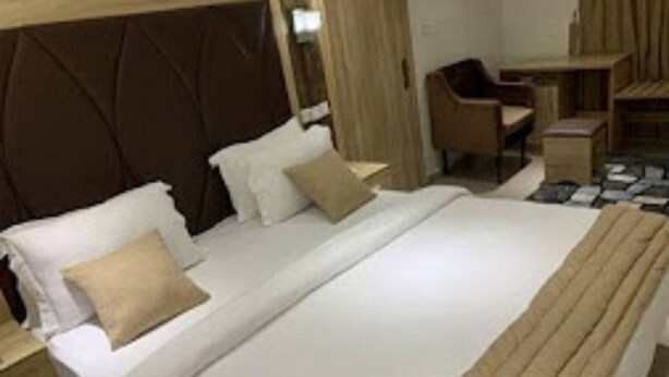 Une chambre d’hôtel avec un grand lit, une tête de lit en bois, un bureau et une chaise.