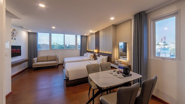 A hotel room with a large bed, a sofa, a dining table, and a TV displaying the Netflix logo. - A25 Premium Hotel - 55 Cach Mang Thang 8 (Ho Chi Minh City)