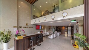 A modern hotel lobby with a reception desk, seating area, and a large mirror reflecting the space. - A25 Premium Hotel - 55 Cach Mang Thang 8 (Ho Chi Minh City)