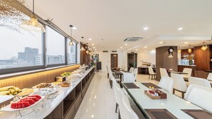 A modern dining area with a long counter, white chairs, and a view of the city through large windows. - A25 Premium Hotel - 55 Cach Mang Thang 8 (Ho Chi Minh City)