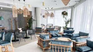 A modern lounge area with wicker furniture, round tables, and hanging lights. - Apartament Morski Widok (Miedzyzdroje)
