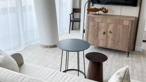A modern living room with a sofa, a round table, a cabinet, and a TV mounted on the wall. - Apartament Morski Widok (Miedzyzdroje)