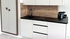 A kitchen with white cabinets, a black countertop, and a wooden backsplash. - Apartament Morski Widok (Miedzyzdroje)