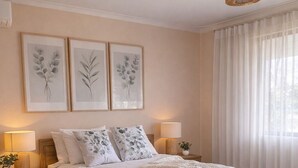 A bedroom with a wooden bed, two bedside tables with lamps, a large window with sheer curtains, and wall-mounted artwork. - Pelicans Rest Albany, 5 min to the beach, 6 min to city. Great all year round! (Collingwood Park)