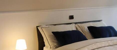 A bedroom with a bed, nightstand, and a wall-mounted abstract painting.