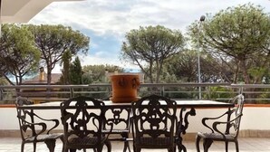 A terrace with a table and chairs, a hanging light fixture, and a view of trees and a building in the background. - Palazzo Excelsus  (Terzigno)