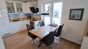 Een moderne keuken met witte kasten, een houten eettafel en zwarte stoelen.