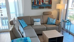Een moderne woonkamer met een hoekbank, een klein bijzettafeltje en een schilderij aan de muur.