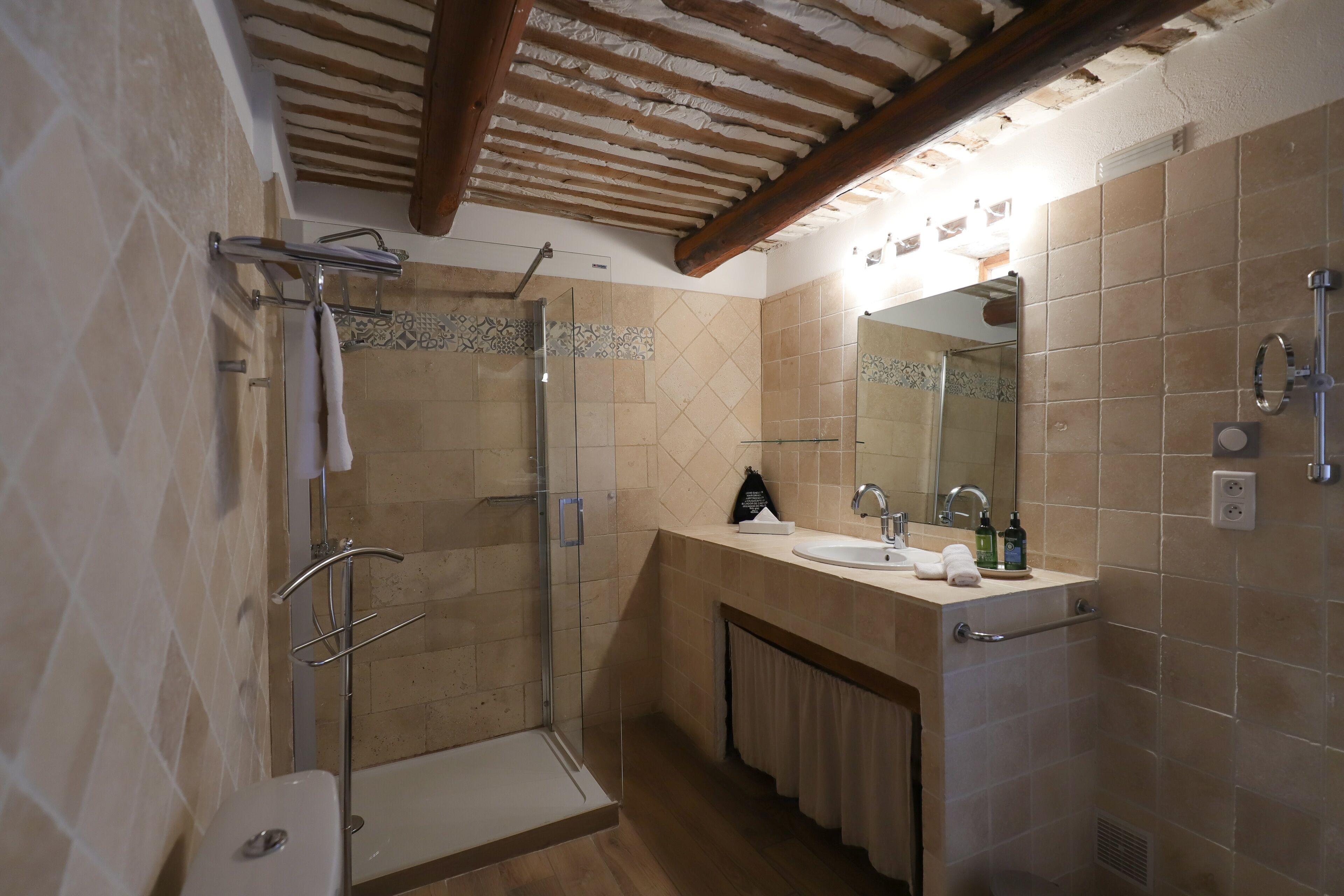 Un baño moderno con cabina de ducha de vidrio, un lavamanos con espejo y un perchero para toallas.