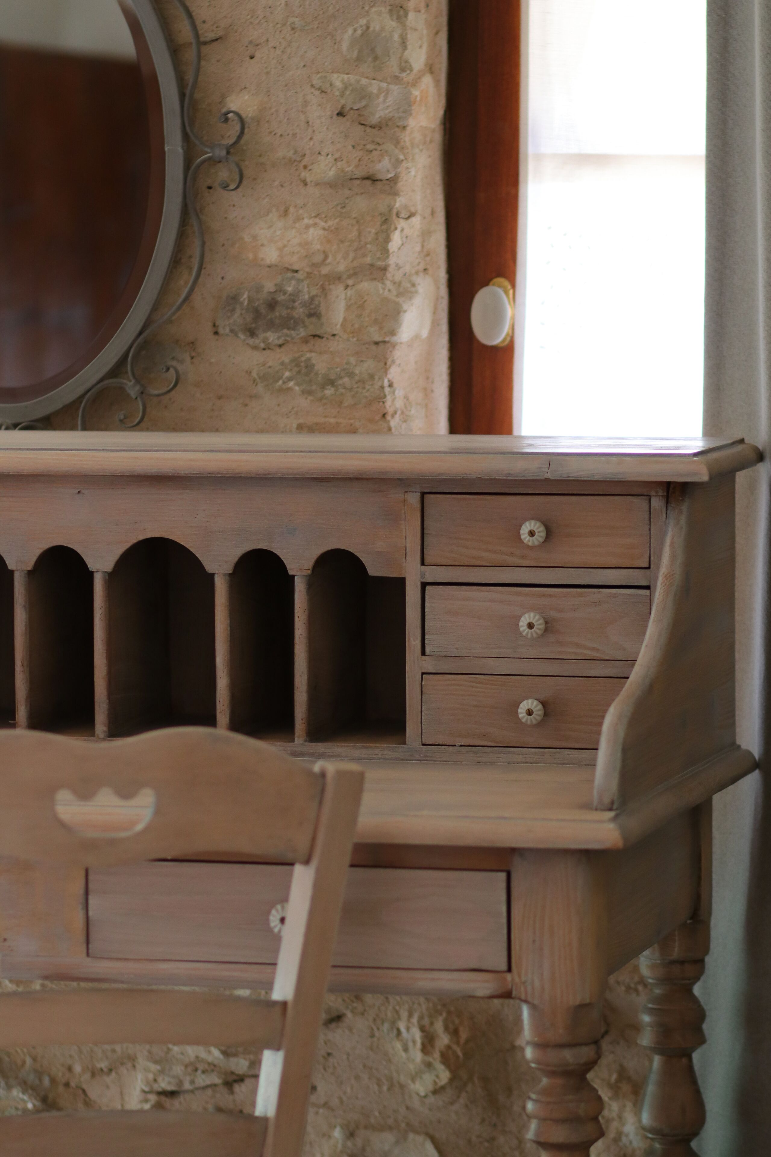 A wooden dresser with drawers and a mirror, set against a stone wall.