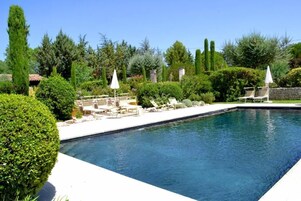 Una piscina al aire libre de temporada, sombrillas, tumbonas