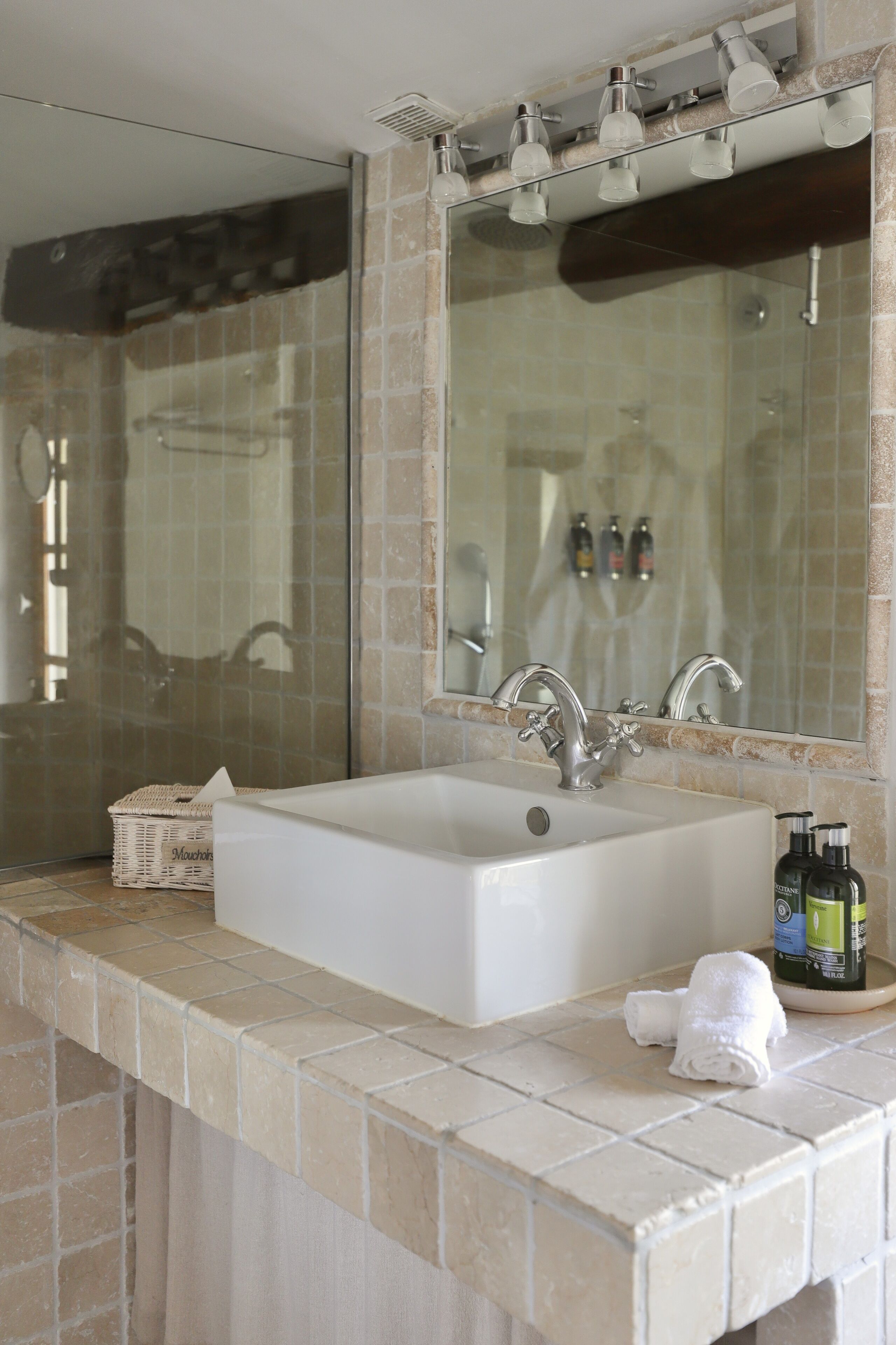 A bathroom with a large mirror, a bathtub, and a sink.