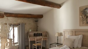 Un dormitorio acogedor con una cama grande, un escritorio de madera y un jarrón con ramas.