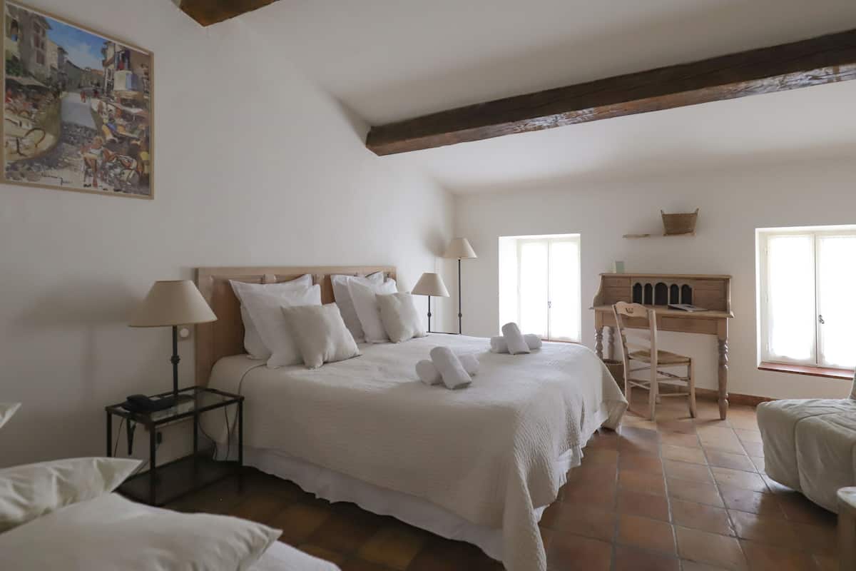 Une chambre à coucher avec un grand lit, des tables de chevet, un bureau et une chaise.