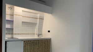 Een kleine keuken met witte tegels, een inbouwgootsteen en een kleine koelkast.