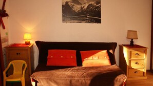 Ein Schlafzimmer mit einem Bett, zwei Nachttischen, einem Sessel und einem Wandbild.