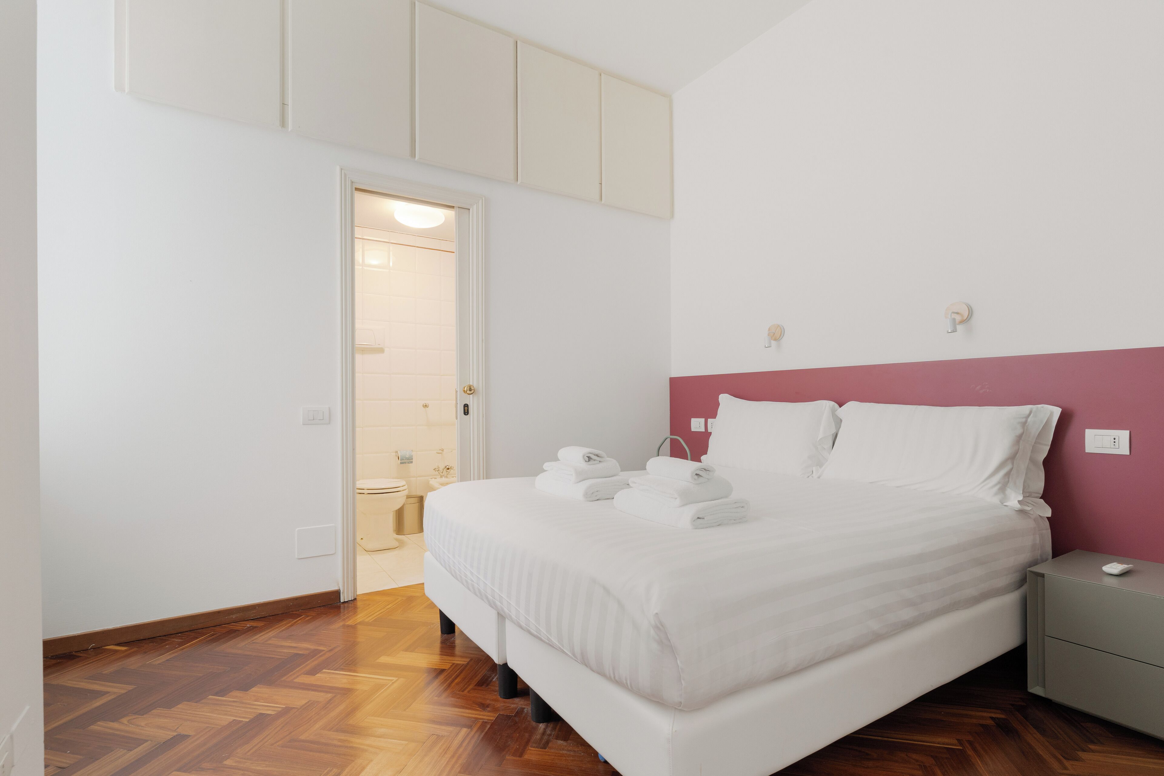 A bedroom with a bed, bedside table, and a door leading to a bathroom.