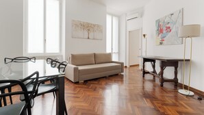 A modern living room with a glass dining table, a beige sofa, and a wooden floor. - Brera Apartments in San Marco (Milan)