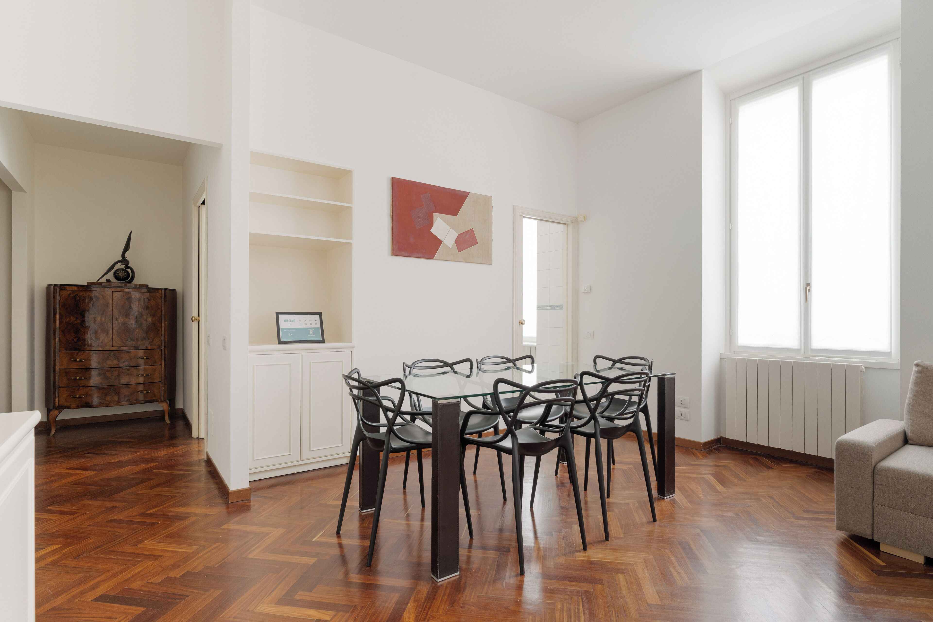 A dining area with a round table and chairs, a wooden cabinet, and a radiator.