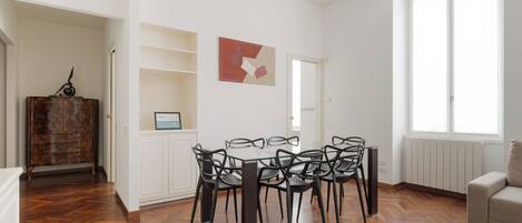 A dining area with a round table and chairs, a wooden cabinet, and a radiator.